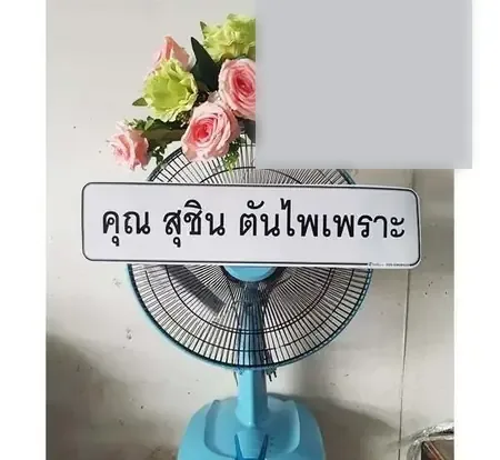 พวงหรีดพัดลมประดับดอกไม้สด ป้ายลงชื่อผู้ส่งเป็นชื่อบุคคล ตั้งอยู่ที่ศาลาวัดในกรุงเทพฯ