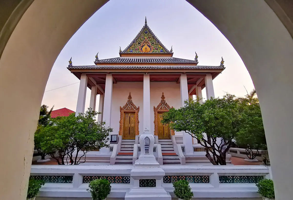 อาคารสีขาวหน้าบันลายไทยในวัดโสมนัส มองผ่านซุ้มโค้ง